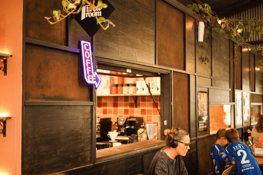 A cozy cafe interior with dark wood paneling, a neon &